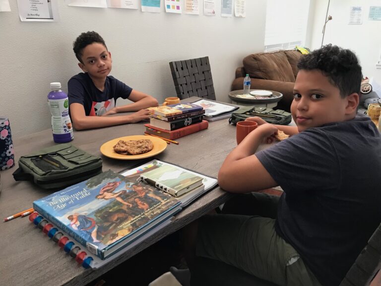 teenage boys eating cookies at dining table waiting for homeschool day to begin