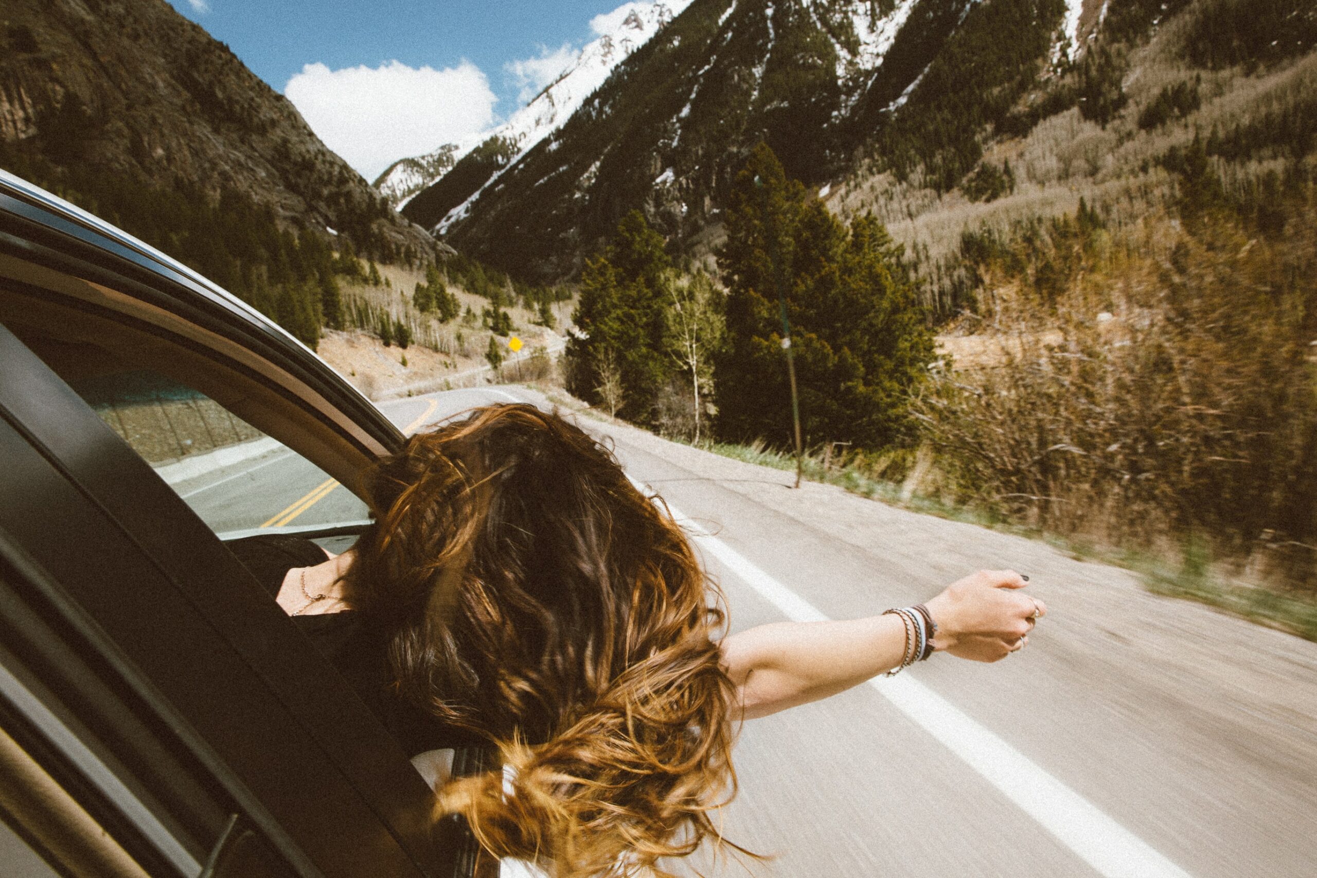 start living unapologetically - woman in car riding with head out window